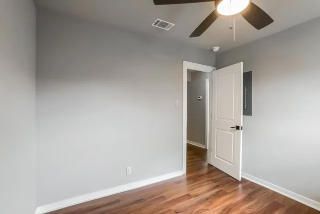 an empty room with wooden floor hallway and a chandelier fan