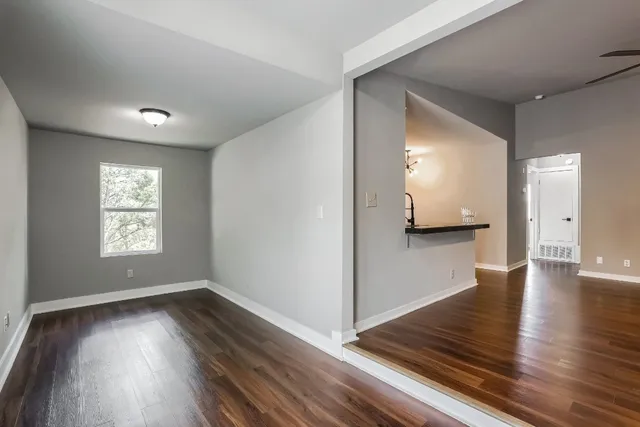 a view of a hallway with wooden floor and a living room