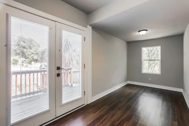 a view of an empty room with wooden floor and a window