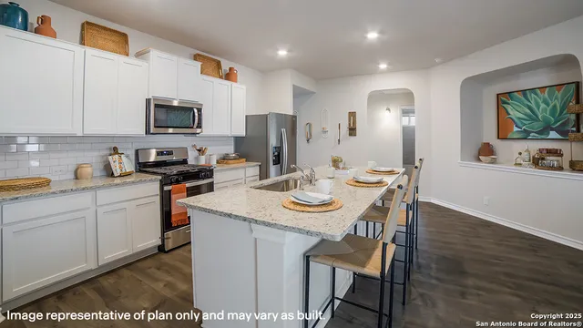 a kitchen with stainless steel appliances kitchen island granite countertop a sink a stove a table and chairs