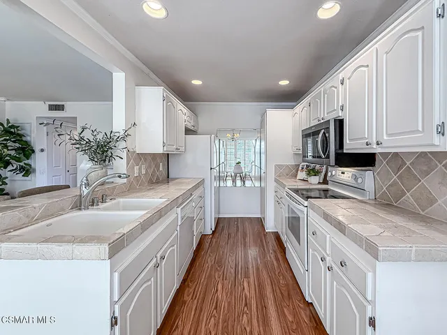 a large kitchen with stainless steel appliances granite countertop a lot of counter space and wooden floors