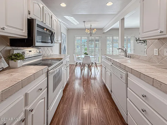 a kitchen with granite countertop a sink a counter space stainless steel appliances and windows