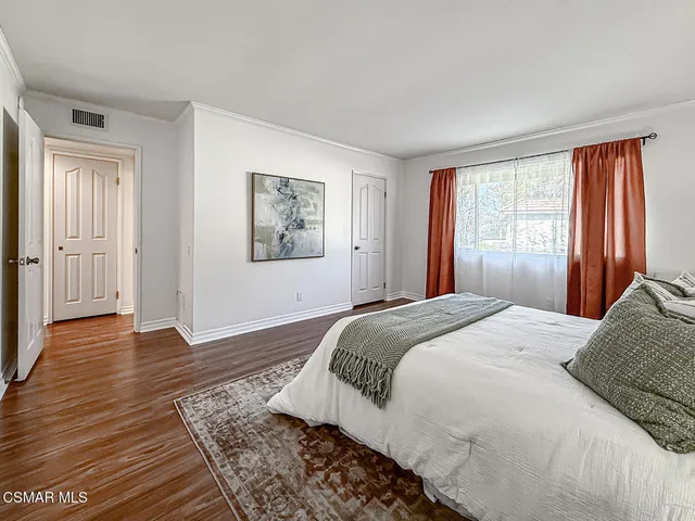 a bedroom with a large bed and wooden floor