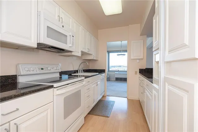 a kitchen with granite countertop white cabinets and appliances