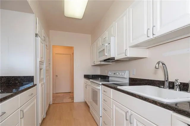 a kitchen with granite countertop white cabinets and a sink