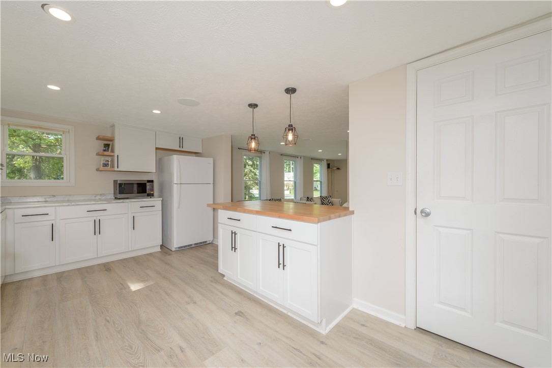 4051 Stow Road Stow, OH 44224 - Photo 15 of 38 Kitchen with light wood-type flooring, white refrigerator, white cabinetry, and decorative light fixtures