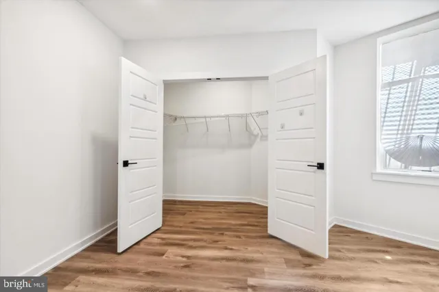 an empty room with wooden floor cabinet and windows
