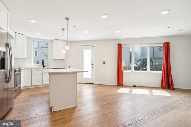 a open kitchen with white cabinets and wooden floor
