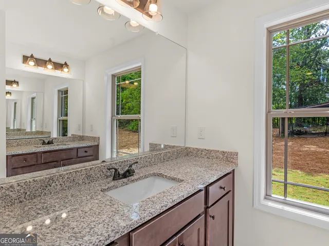 a bathroom with a granite countertop sink and a large mirror