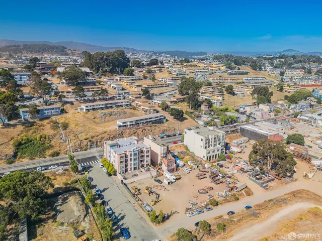 an aerial view of ocean and residential houses with outdoor space