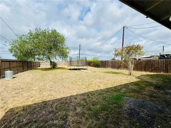 a swimming pool with yard and tree in front of it