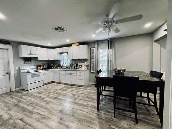 a kitchen with a table chairs a sink dishwasher refrigerator and cabinets