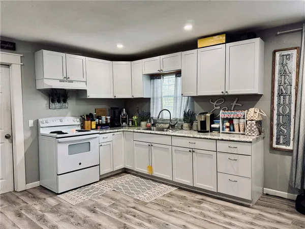 a kitchen with granite countertop white cabinets and white appliances