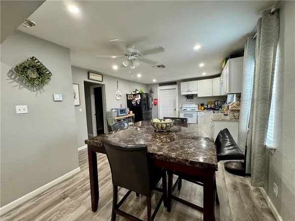 a kitchen with stainless steel appliances granite countertop a dining table chairs refrigerator and cabinets
