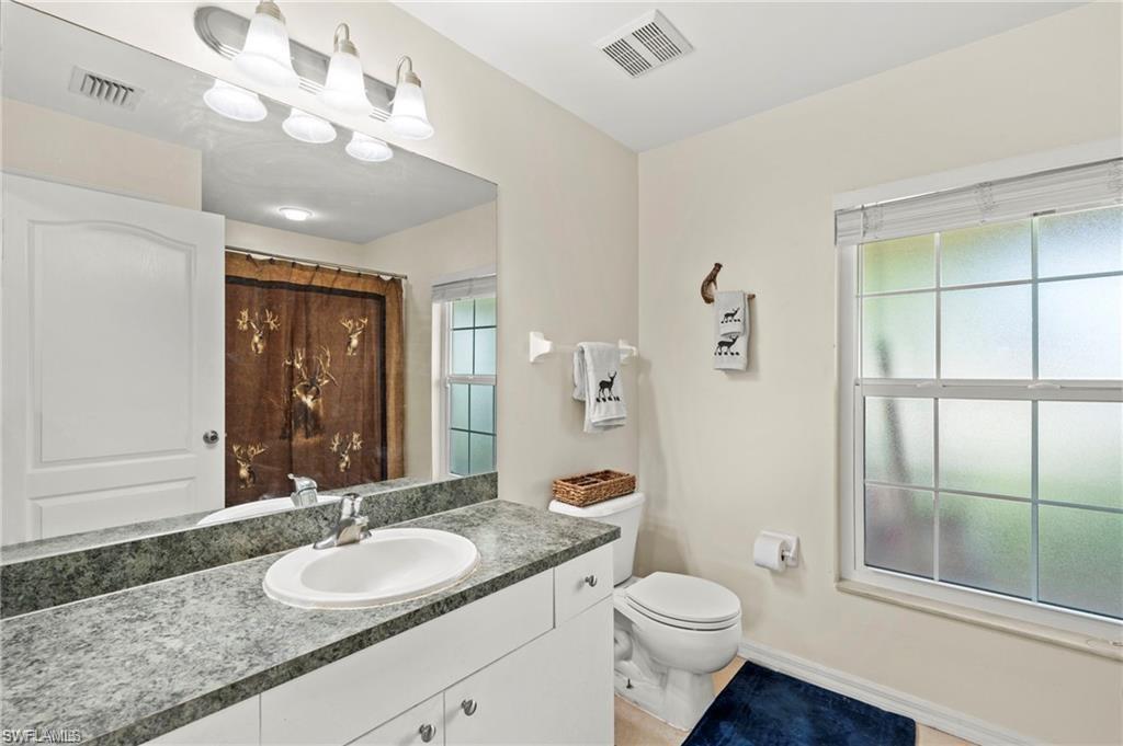 3303 32nd Street Southwest Lehigh Acres, FL 33976 - Photo 13 of 35 a bathroom with a granite countertop double vanity sink a mirror and a toilet