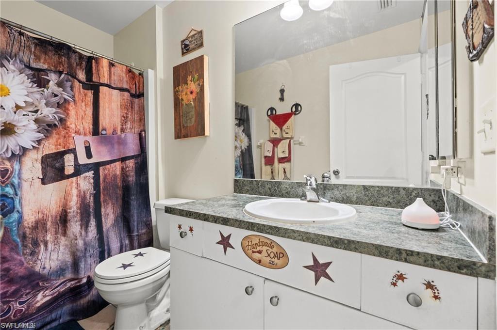 3303 32nd Street Southwest Lehigh Acres, FL 33976 - Photo 16 of 35 a bathroom with a granite countertop toilet sink and mirror
