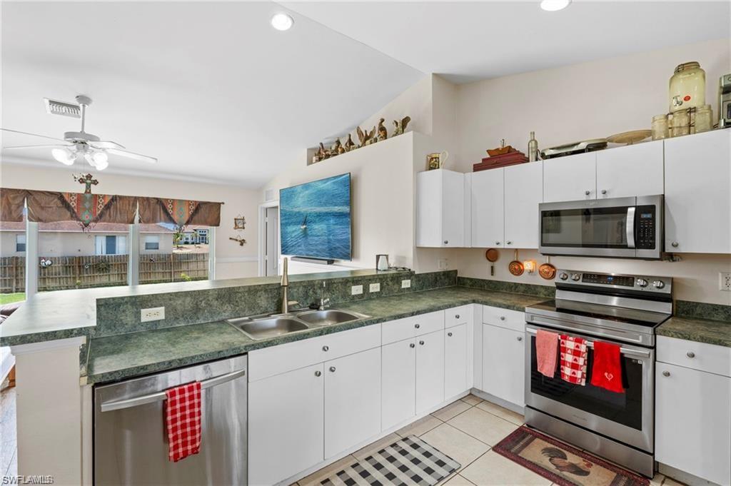 3303 32nd Street Southwest Lehigh Acres, FL 33976 - Photo 6 of 35 a kitchen with stainless steel appliances granite countertop a stove a sink and a microwave