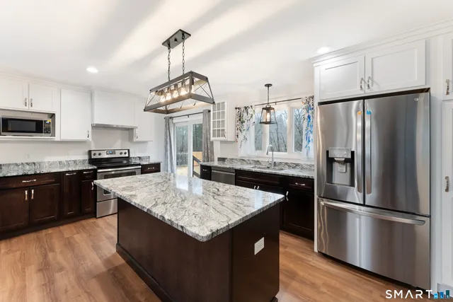 a kitchen with granite countertop a refrigerator a stove and a sink