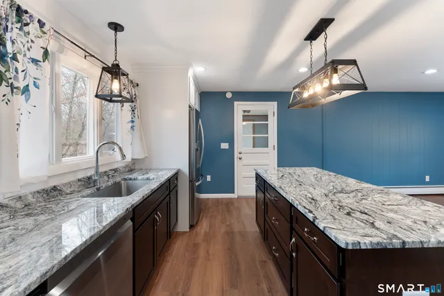 a kitchen with kitchen island granite countertop a sink stove and cabinets
