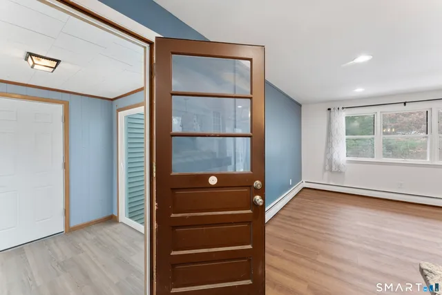 an empty room with wooden floor closet and windows