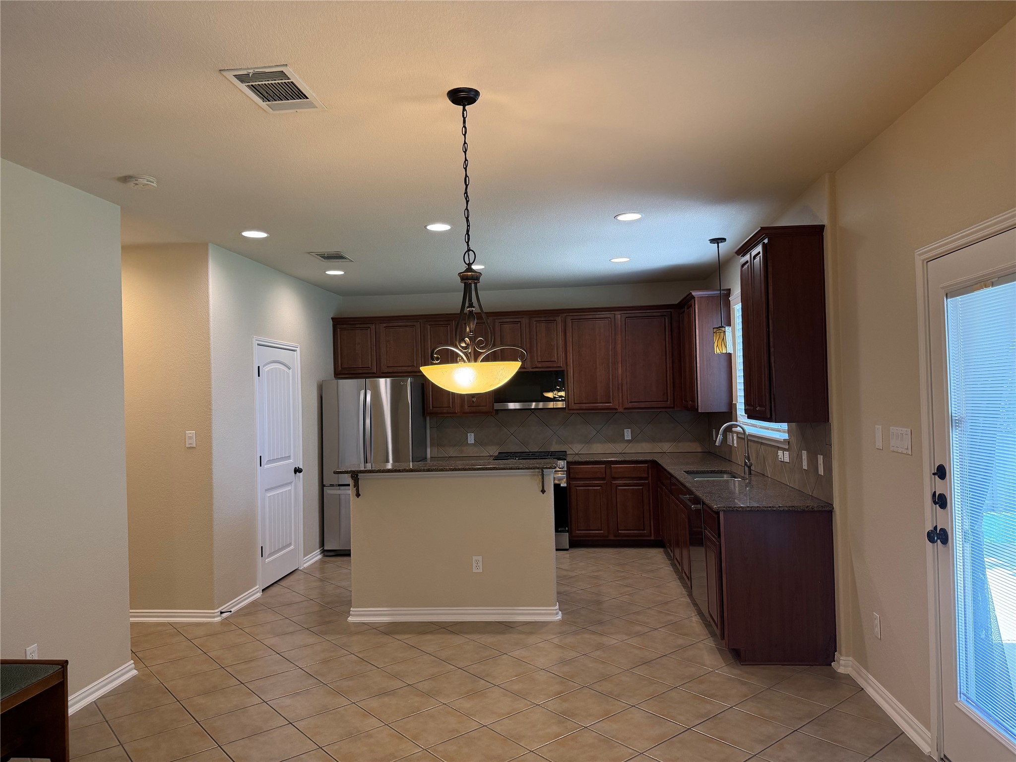 3021 Grand Mission Way Pflugerville, TX 78660 - Photo 11 of 31 A functional kitchen boasts dark wood cabinetry and ample countertop space.