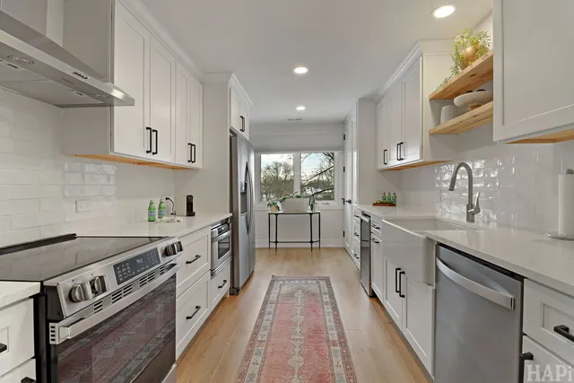 a kitchen with a sink dishwasher stove and white cabinets