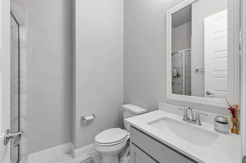 7852 Buffaloberry Road Frisco, TX 75035 - Photo 21 of 36 Modern secondary bathroom downstairs featuring a single vanity with a white countertop and undermount sink, chrome faucet, and a framed mirror