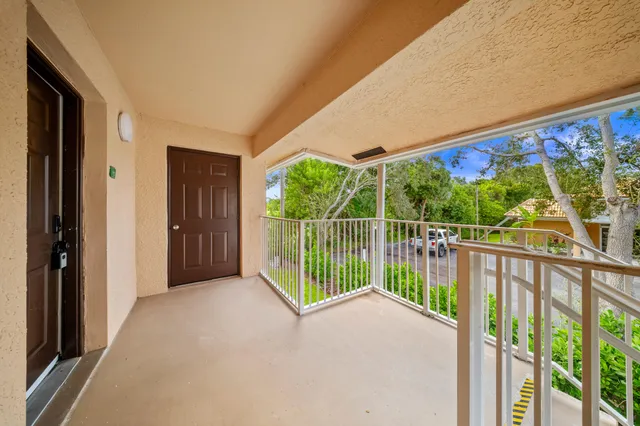 a view of a white house with a big yard and potted plants and a fountain
