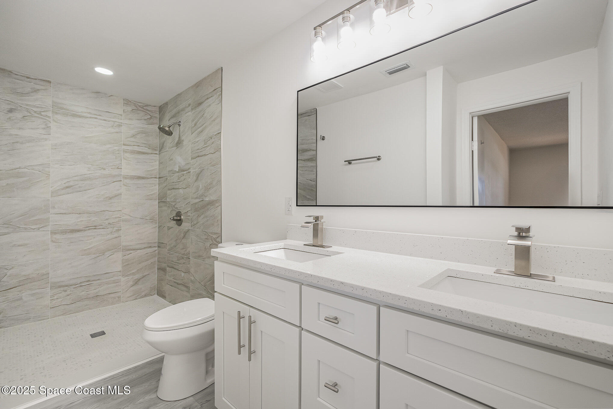 906 Kings Post Road Rockledge, FL 32955 - Photo 11 of 31 a bathroom with a toilet a sink a mirror a shower and vanity