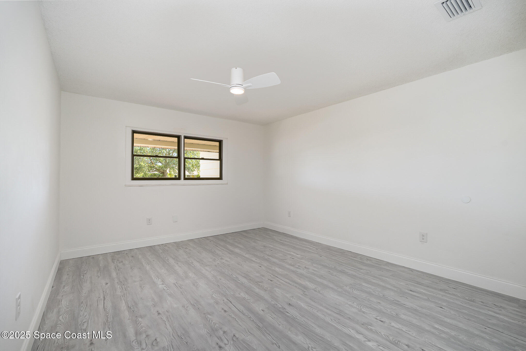906 Kings Post Road Rockledge, FL 32955 - Photo 13 of 31 an empty room with wooden floor and windows