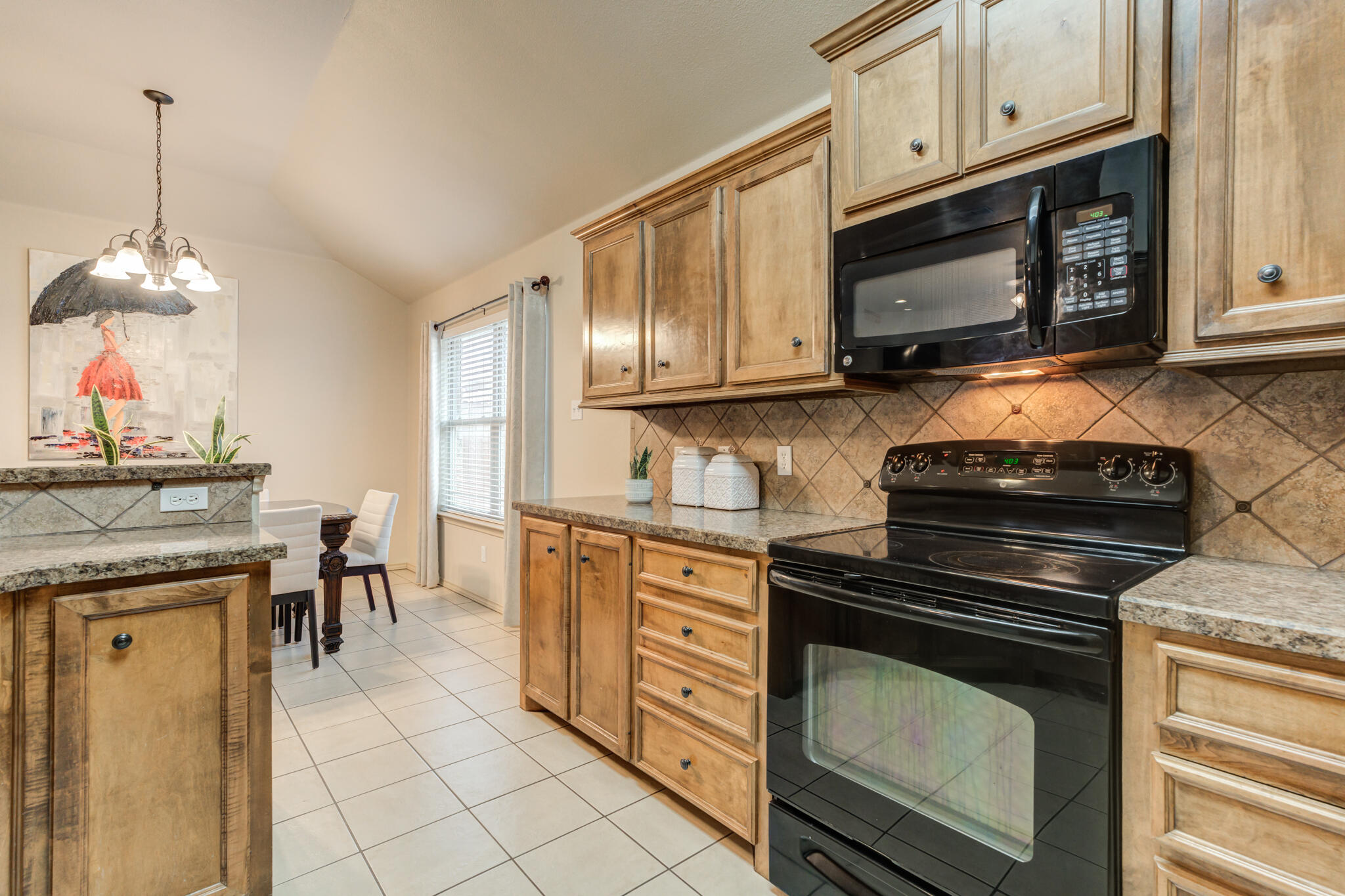 2206 101st Street Lubbock, TX 79423 - Photo 21 of 37 a kitchen with granite countertop a stove top oven microwave and cabinets