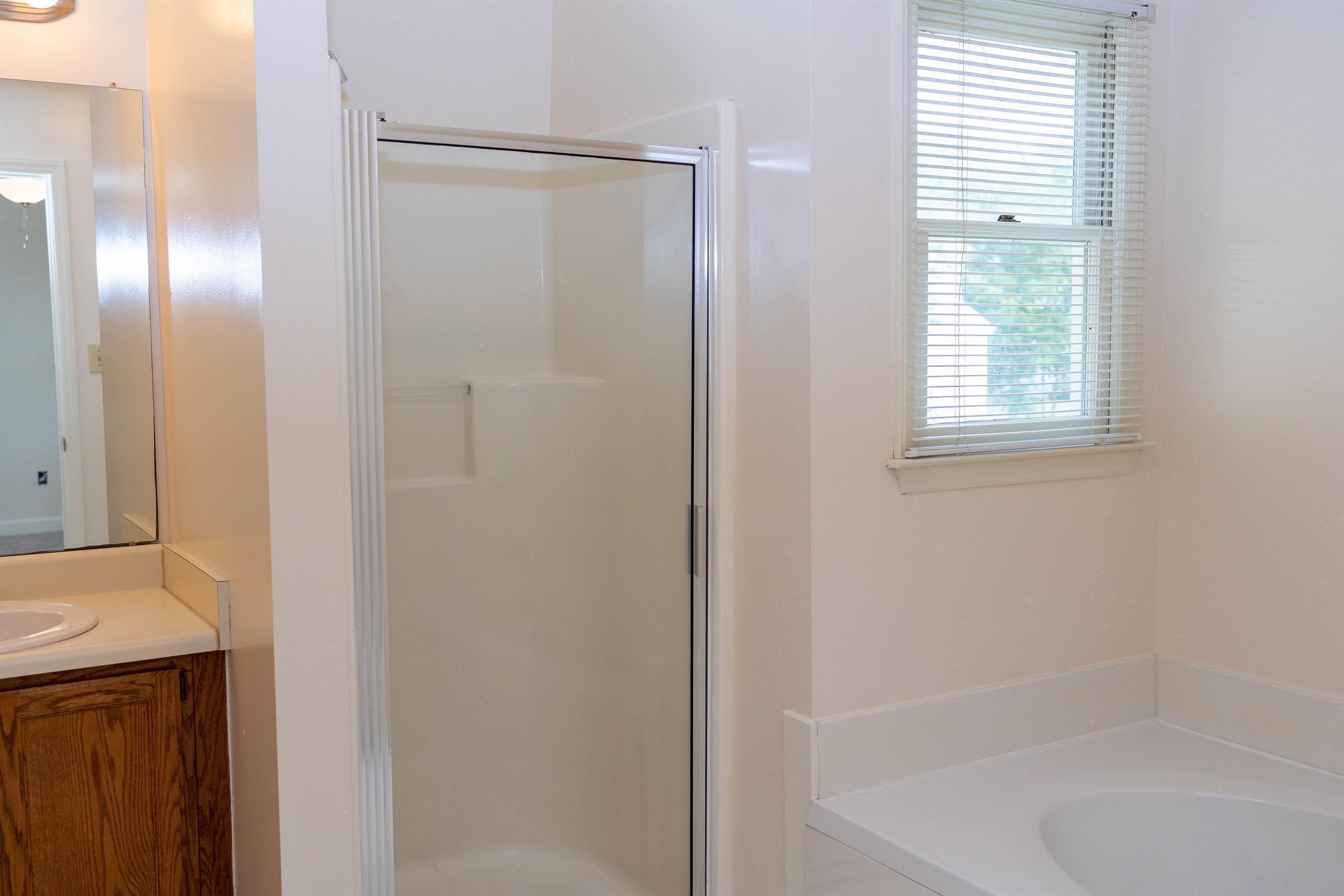 2704 Moorsfield Court Raleigh, NC 27604 - Photo 15 of 25 a bathroom with a bathtub a shower and a window