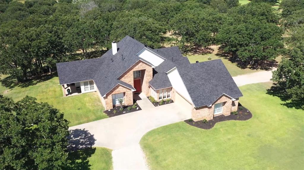an aerial view of a house with swimming pool and large trees