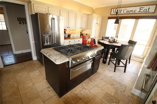 a kitchen with stainless steel appliances granite countertop a stove a refrigerator and a dining table with granite countertop