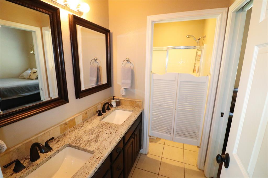 2642 Huddleston Road Sunset, TX 76270 - Photo 21 of 40 a bathroom with a granite countertop sink and a mirror