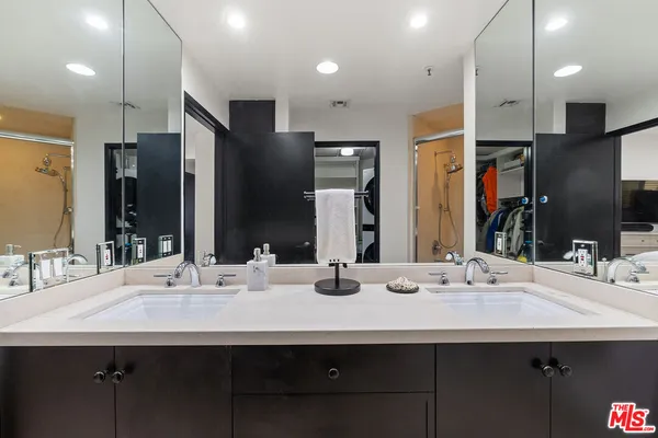 a bathroom with double vanity sinks a large mirror and shower