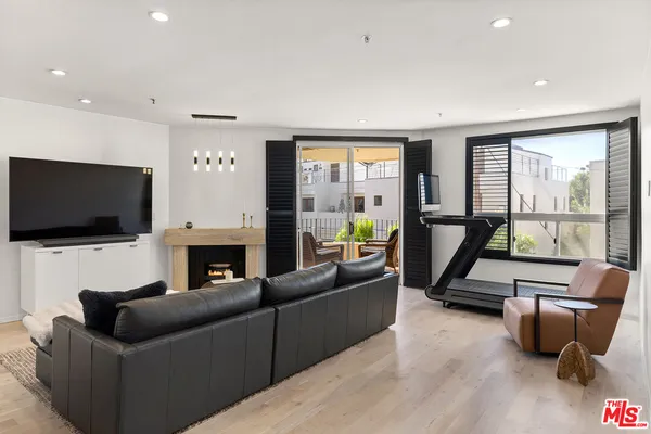 a living room with furniture floor to ceiling window hardwood floor and a flat screen tv