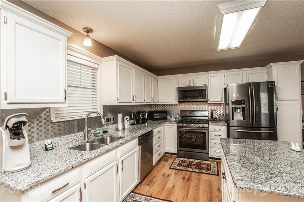 1360 Mistletoe Ridge Place Northwest Concord, NC 28027 - Photo 11 of 38 a kitchen with stainless steel appliances granite countertop a sink stove microwave and refrigerator