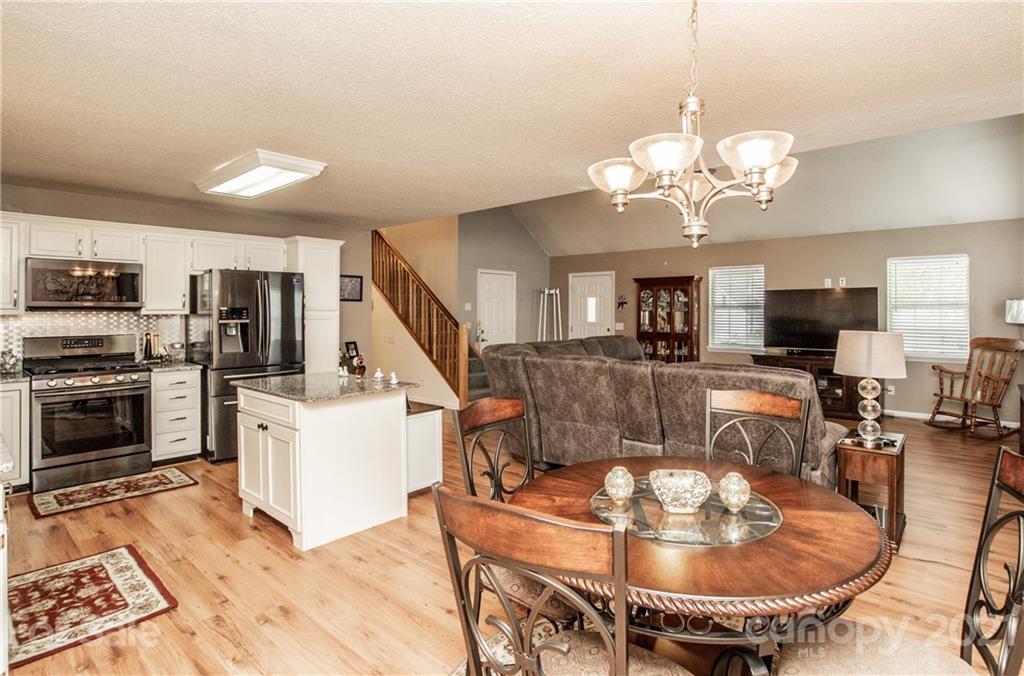 1360 Mistletoe Ridge Place Northwest Concord, NC 28027 - Photo 14 of 38 a living room with dining table a flat screen tv and kitchen view