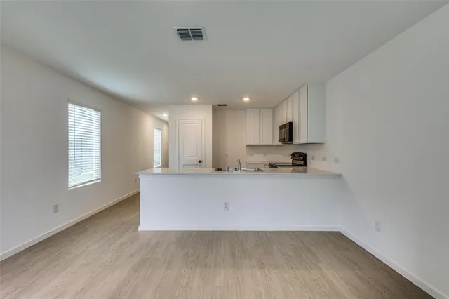 a living room with stainless steel appliances granite countertop a couch wooden floor and a window