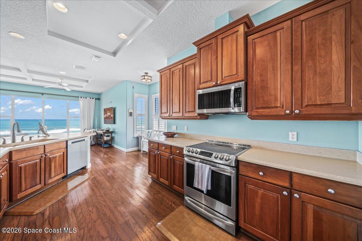 7585 South Hwy A1A Melbourne Beach, FL 32951 - Photo 13 of 45 a kitchen with stainless steel appliances granite countertop wooden cabinets a stove top oven a sink and dishwasher