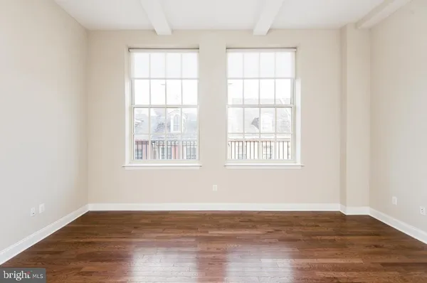 a view of an empty room with wooden floor and a window