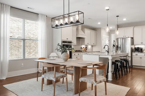 a kitchen with kitchen island granite countertop a dining table chairs and wooden floor