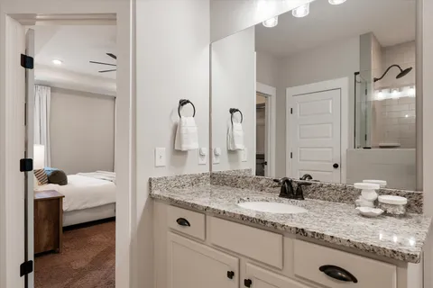 a en suite bathroom with a granite countertop sink and a mirror