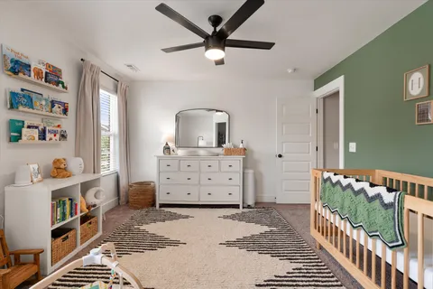 a view of a bedroom with baby crib and lounge chair