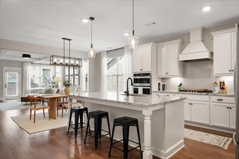 a large kitchen with stainless steel appliances kitchen island granite countertop a table chairs sink and cabinets