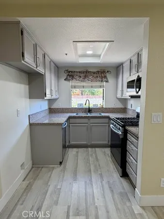 a kitchen with stainless steel appliances granite countertop a sink cabinets and wooden floor