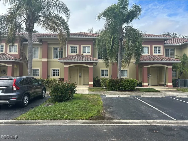 a view of a brick house with a yard plants and palm trees