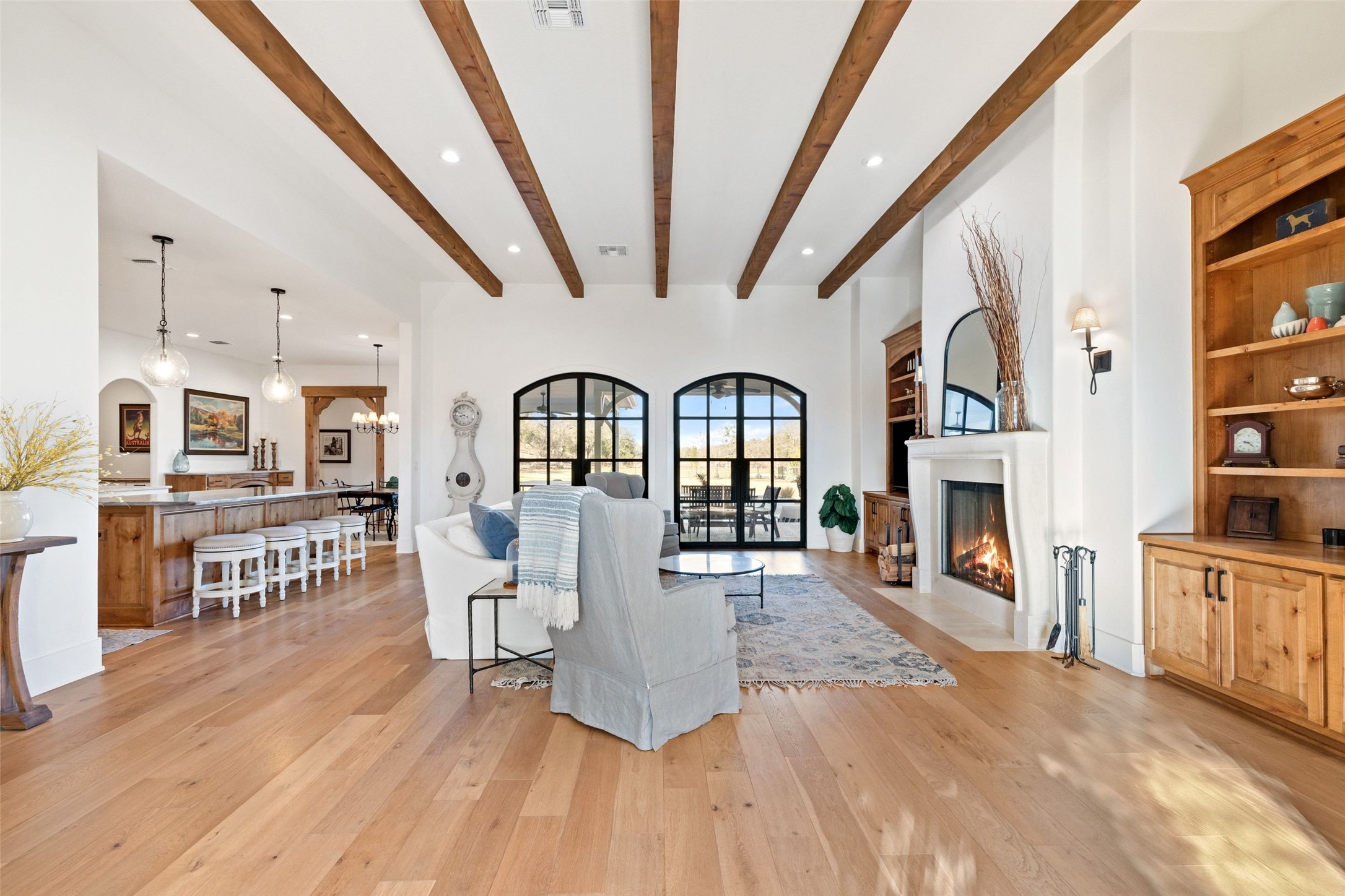 105 Deer Valley Road Georgetown, TX 78628 - Photo 6 of 40 Living area with built in features, a fireplace with flush hearth, light wood finished floors, beamed ceiling, and suspended lighting