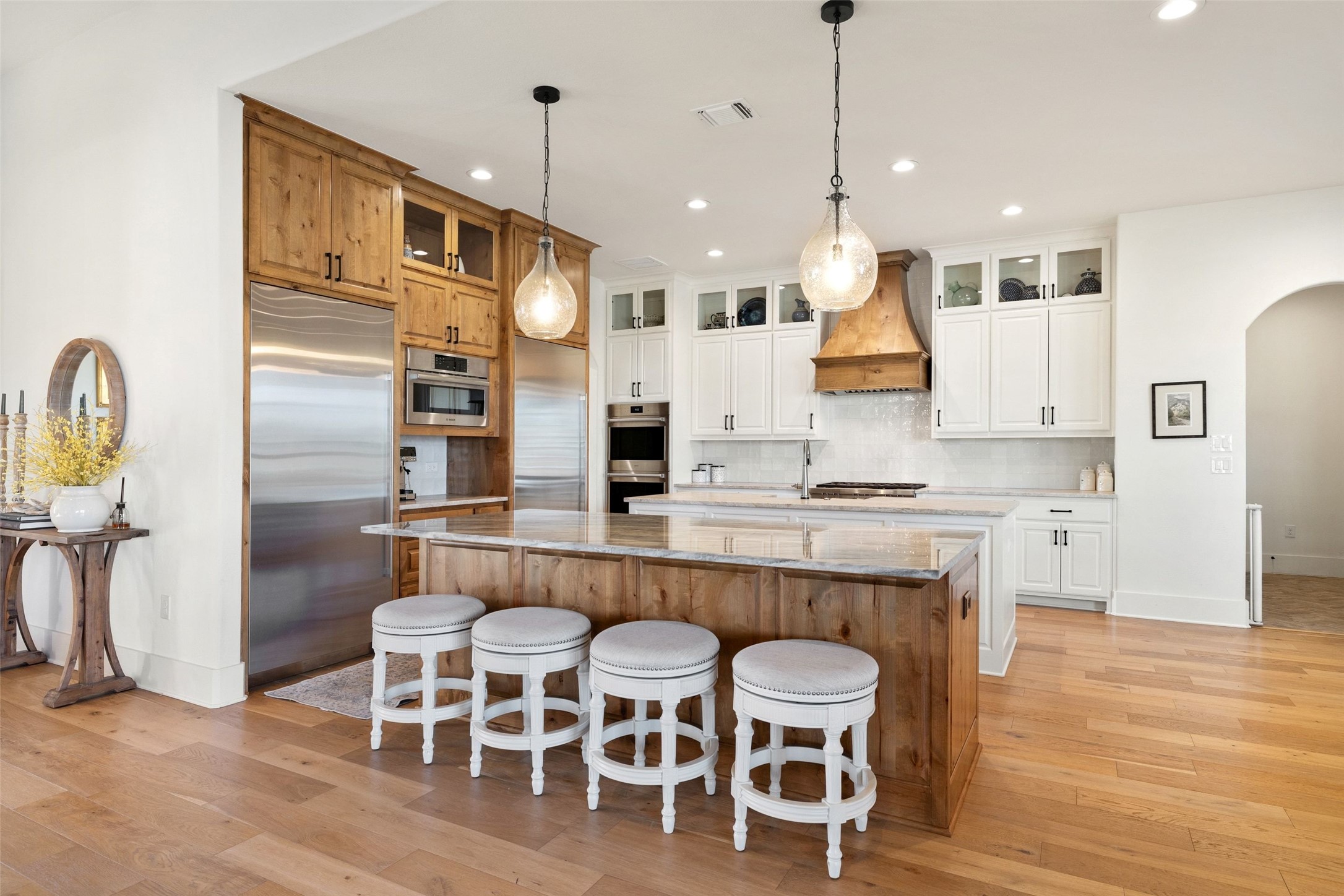 105 Deer Valley Road Georgetown, TX 78628 - Photo 8 of 40 Kitchen featuring arched walkways, stainless steel appliances, light wood finished floors, an island with sink, and light stone countertops